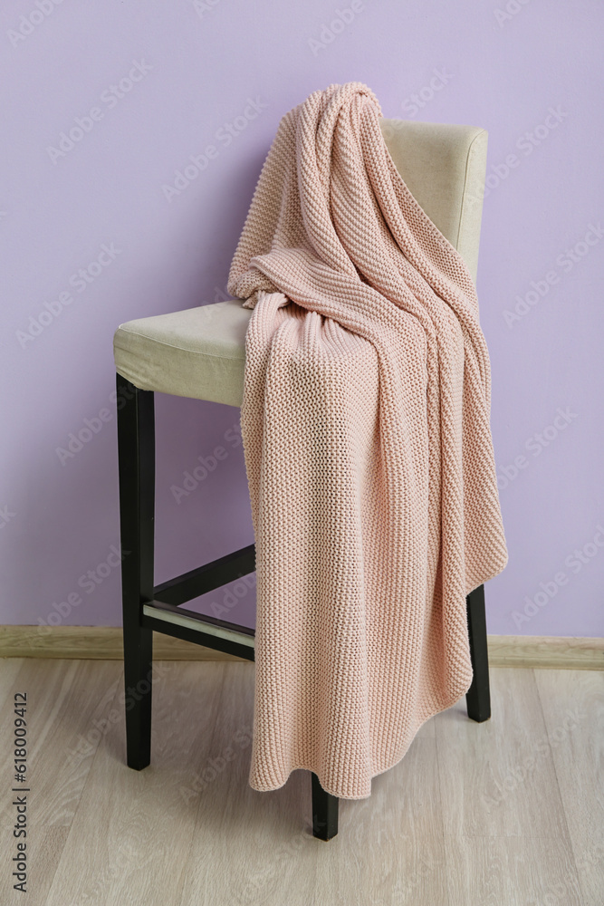 New soft blanket on chair near purple wall in room