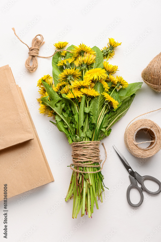 Bouquet of beautiful dandelion flowers, rope, scissors and books on light background, closeup