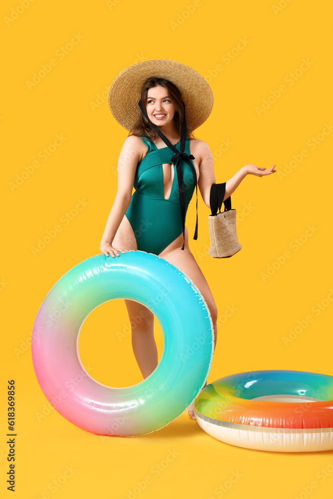 Young woman with bag and swim rings on yellow background