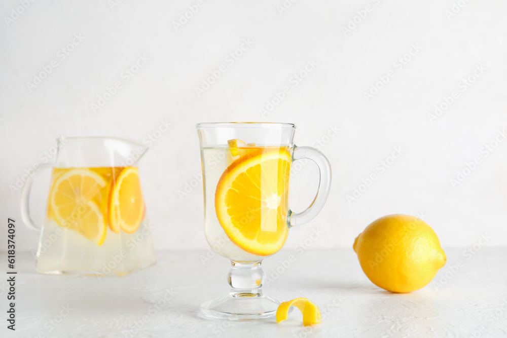 Glass cup of infused water with lemon on light background
