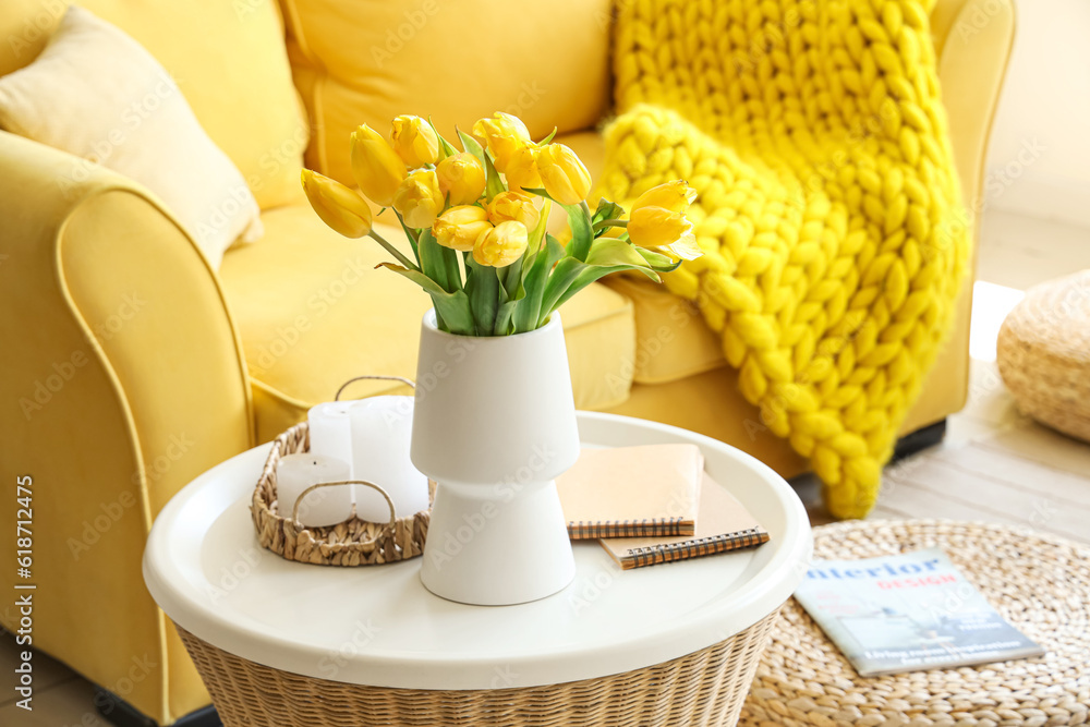 Vase with blooming tulip flowers on coffee table in interior of living room