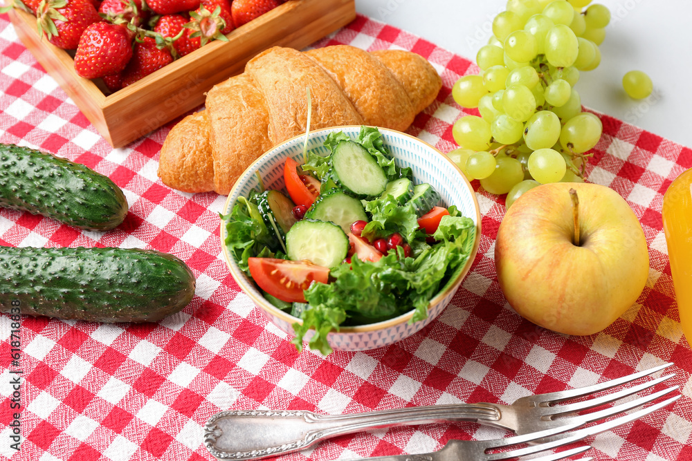 Bowl with tasty salad and food for picnic on white background, closeup