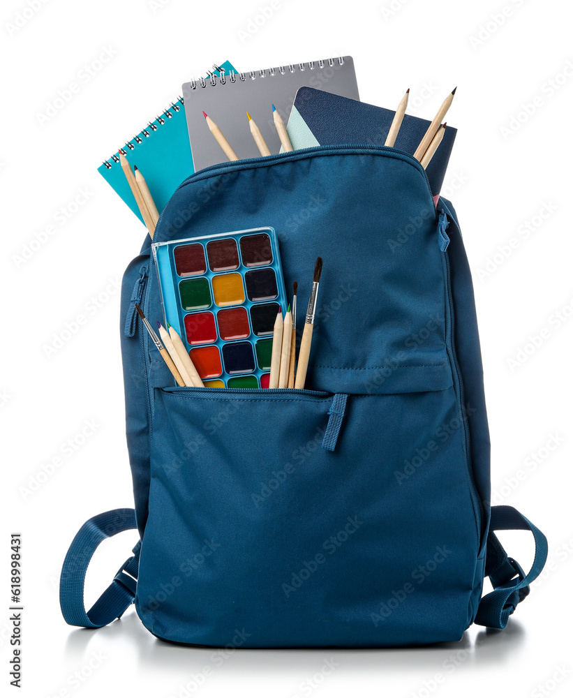 Blue school backpack with notebooks, color pencils and watercolors on white background