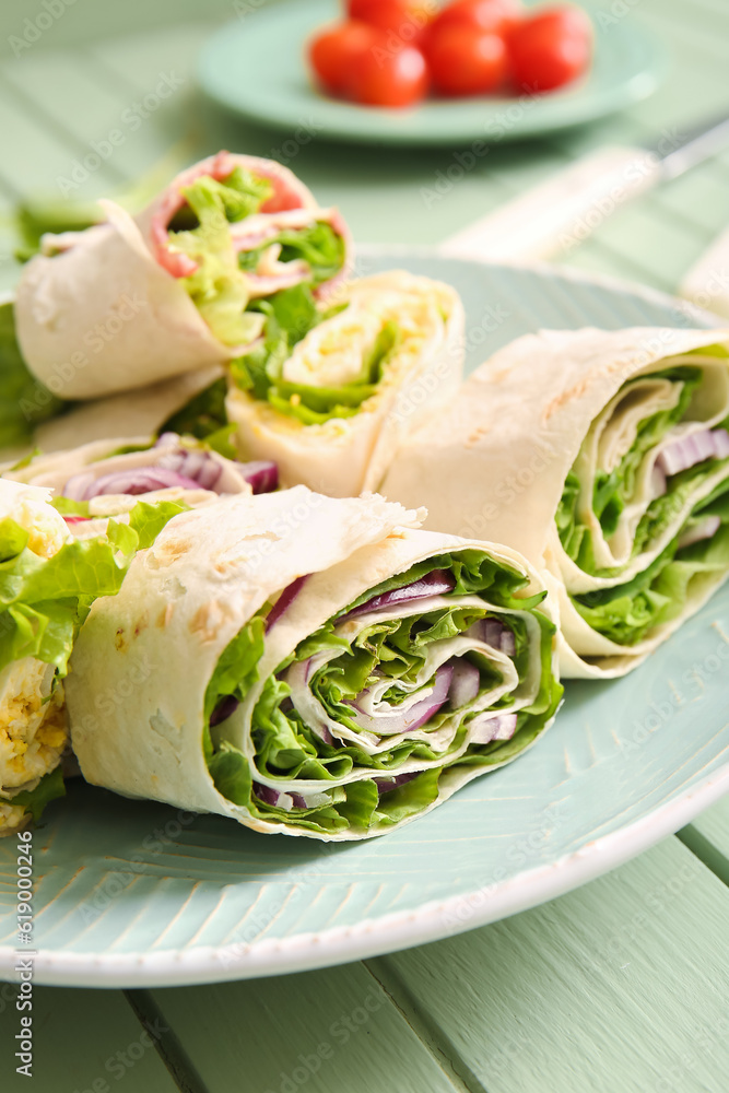Plate of tasty lavash rolls with onion and greens on table