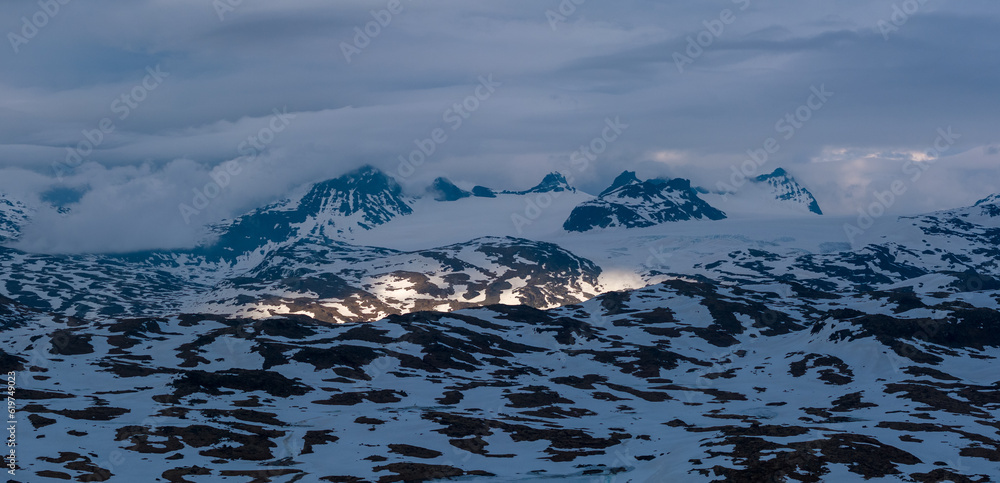 Dramatic landscape of misty mountains with a small spotlight on the slope