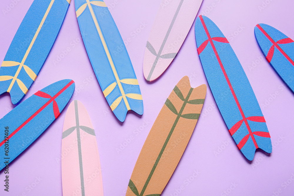 Many different colorful mini surfboards on lilac background