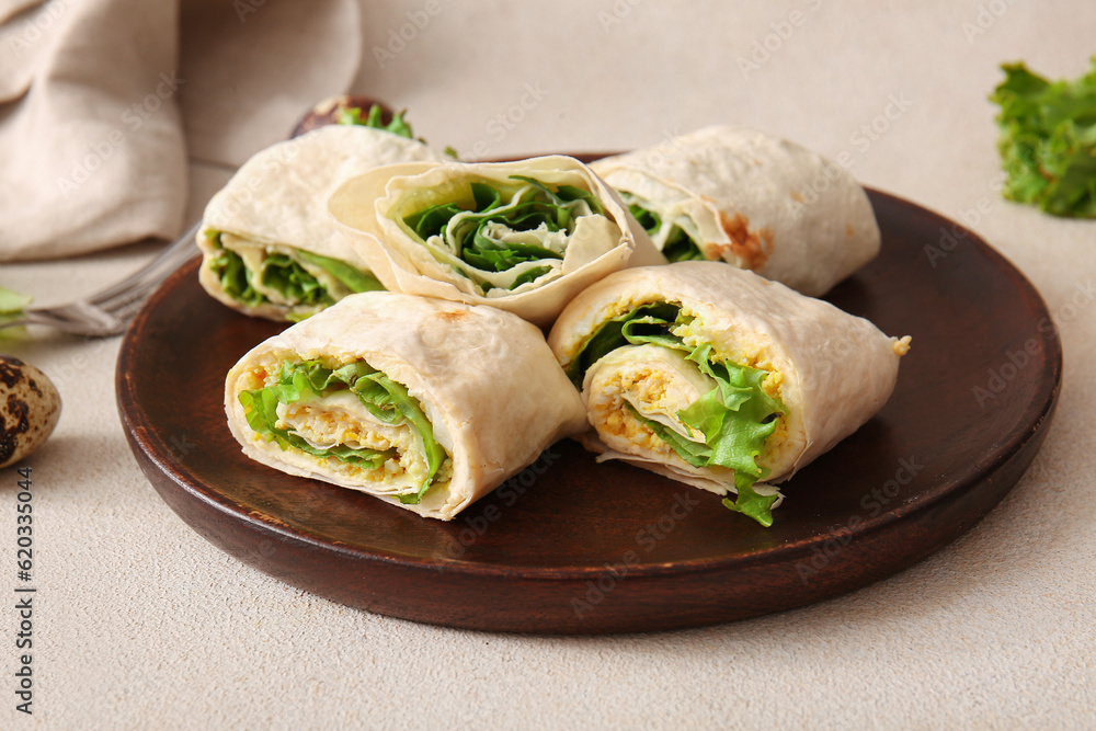 Plate of tasty lavash rolls with egg and greens on light background