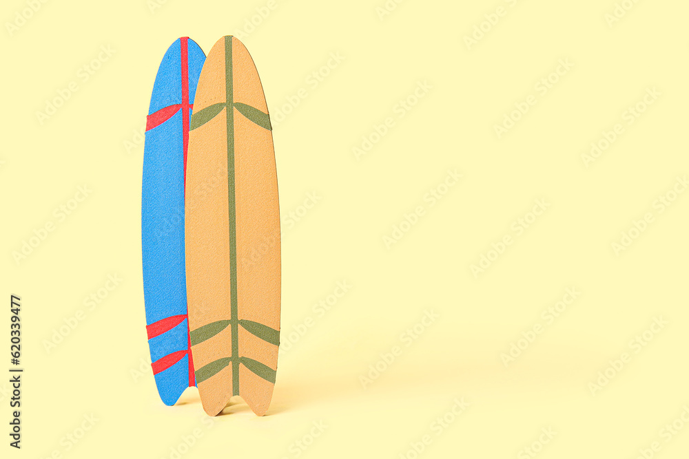 Different mini surfboards on pale yellow background