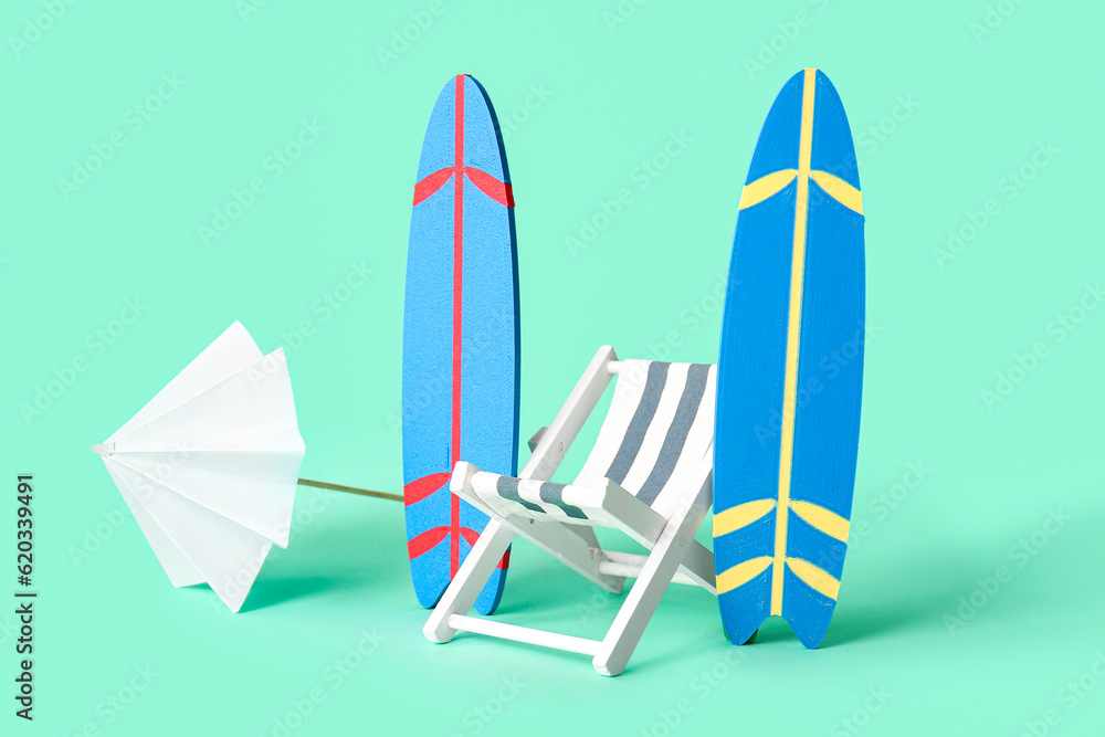 Composition with mini surfboards, umbrella and deckchair on turquoise background