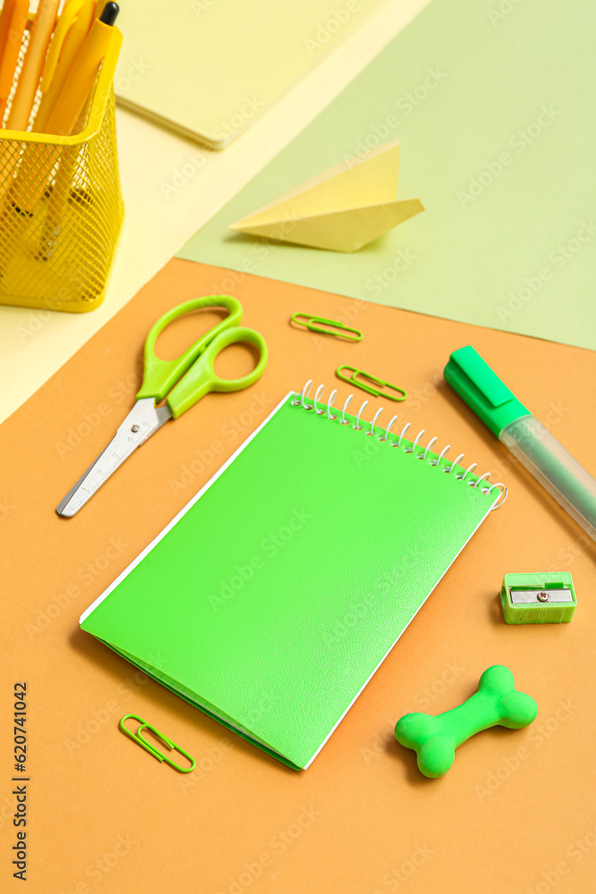 Notebook and school stationery on color background, closeup