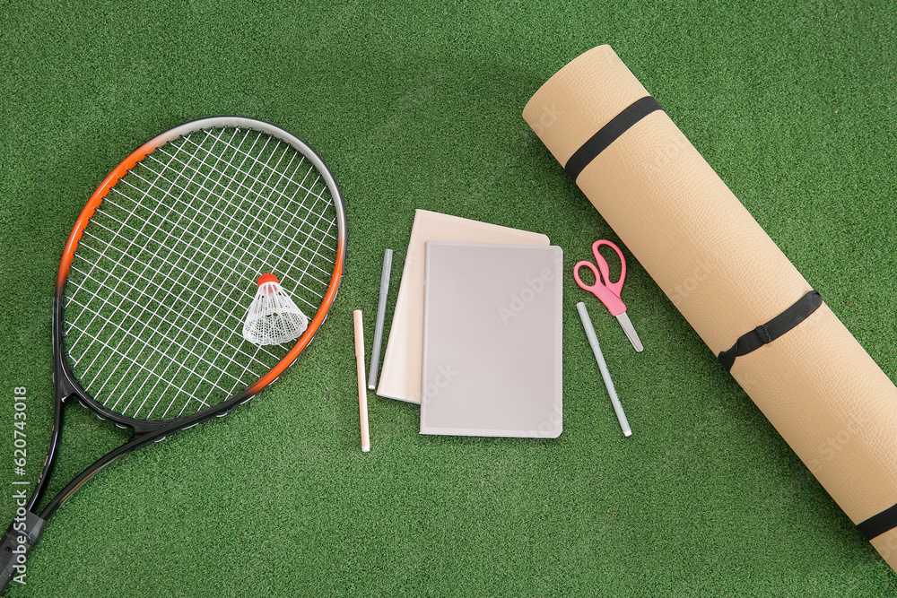 Yoga mat with racket, badminton shuttlecock and different stationery on color background