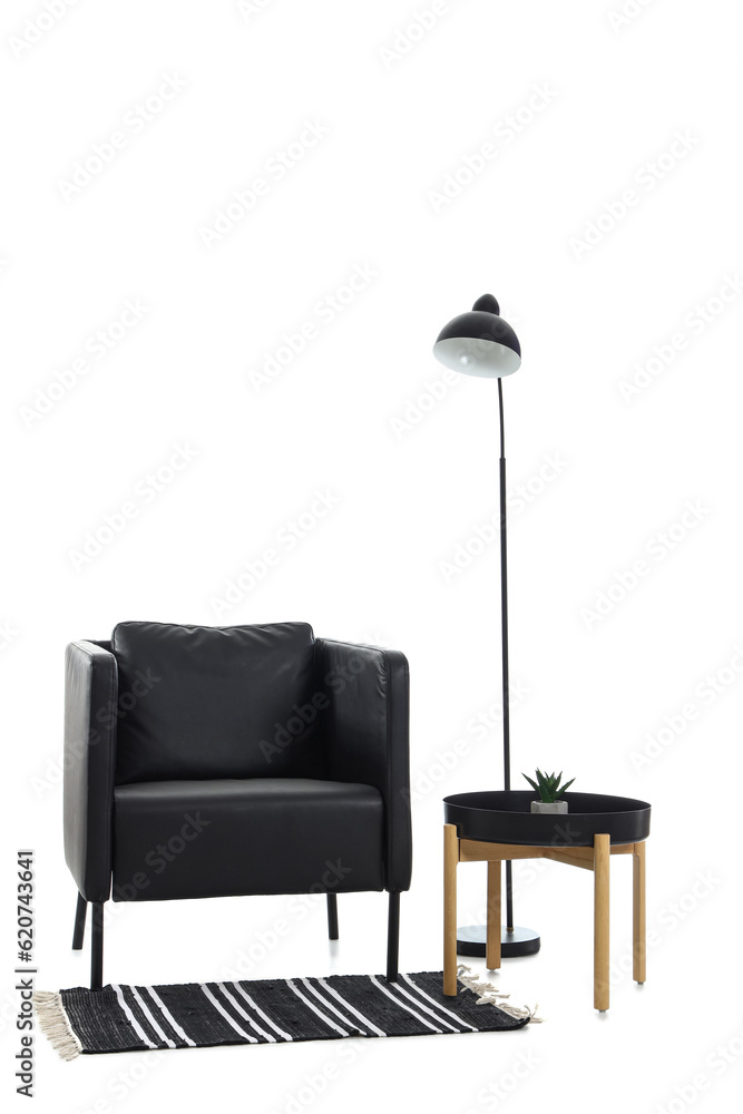 Black armchair with table, lamp and rug on white background