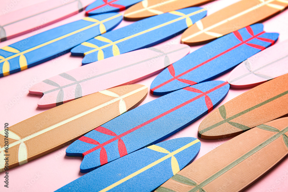 Many different colorful mini surfboards on pink background