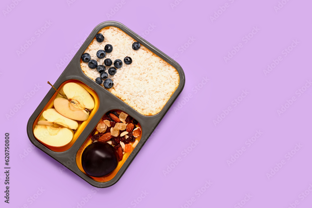 Lunchbox with tasty food on lilac background