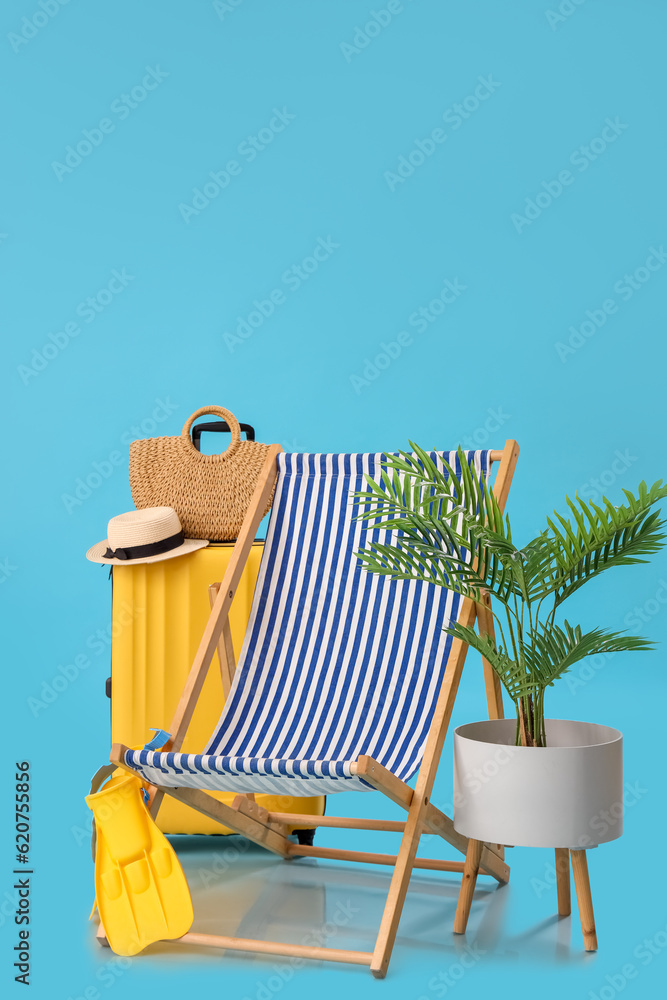 Deck chair with suitcase, beach accessories and palm tree on blue background