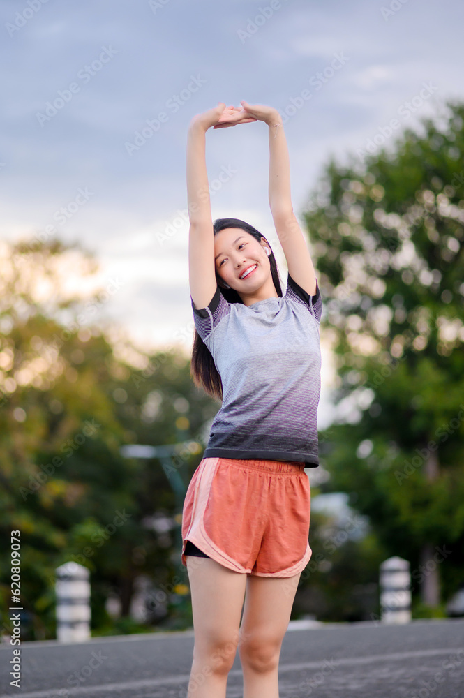 Young Asian woman workout fitness exercising preparing for run outdoors on road in park