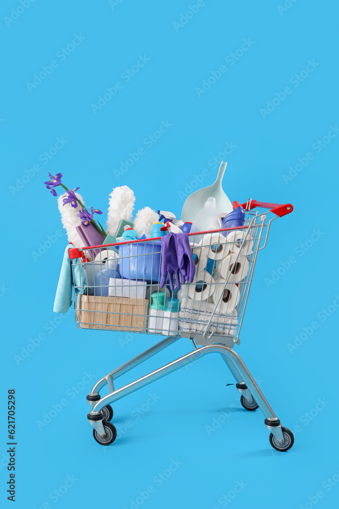 Shopping cart full of cleaning supplies and purple flowers on blue background