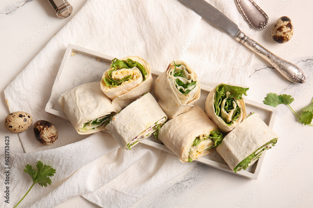 Plate of tasty lavash rolls with egg, onion and greens on white marble background