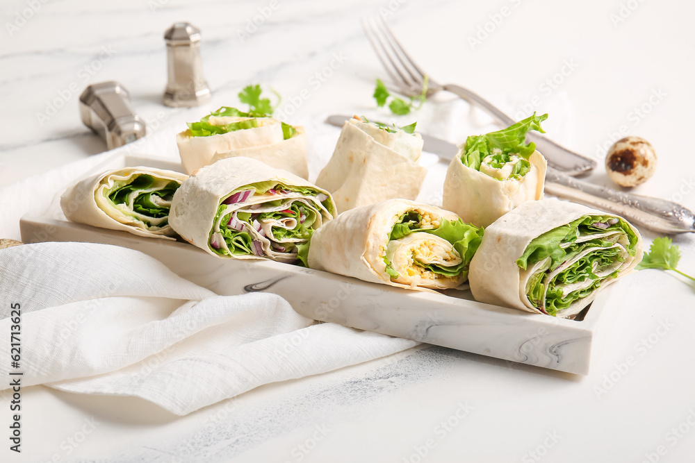 Plate of tasty lavash rolls with egg, onion and greens on white marble background