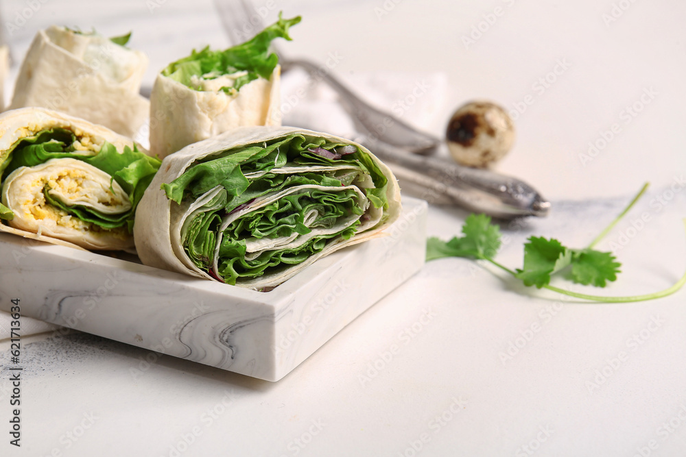 Plate of tasty lavash rolls with onion and greens on white marble background