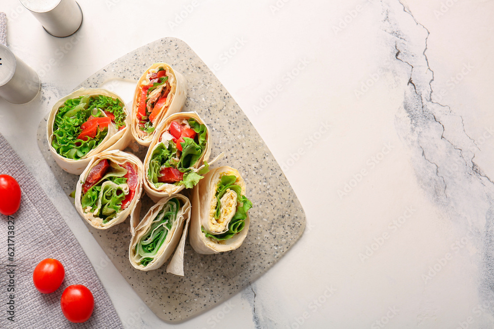 Board of tasty lavash rolls with tomatoes, egg and greens on white marble background