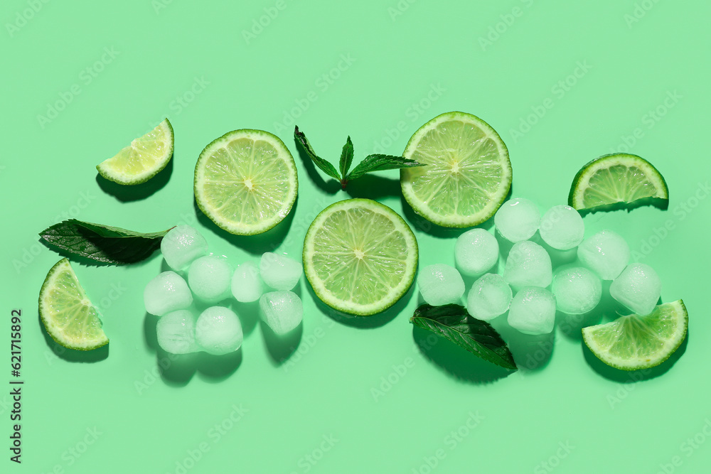 Lime slices with ice cubes and mint on green background