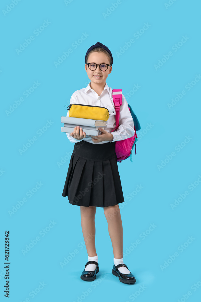Little schoolgirl with backpack, pencil case and books on blue background
