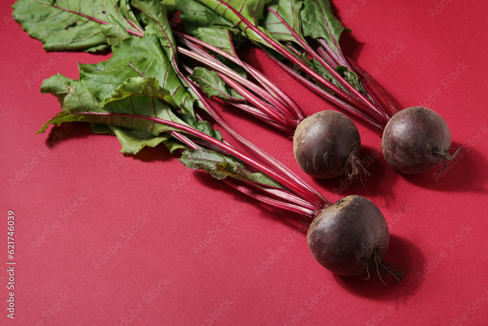 Fresh beetroots with leaves on red background