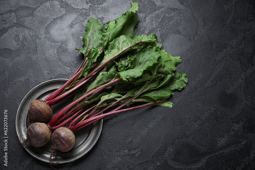 Plate with fresh beetroots on black table