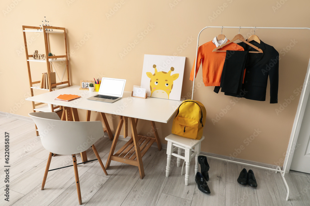 Stylish interior of childrens room with modern laptop and school uniform