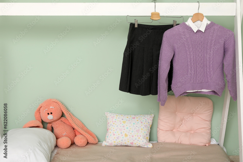 Stylish school uniform hanging on comfortable bed in childrens room, closeup