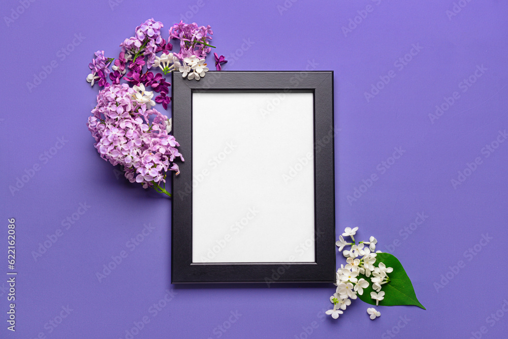 Composition with beautiful lilac flowers and blank frame on blue background
