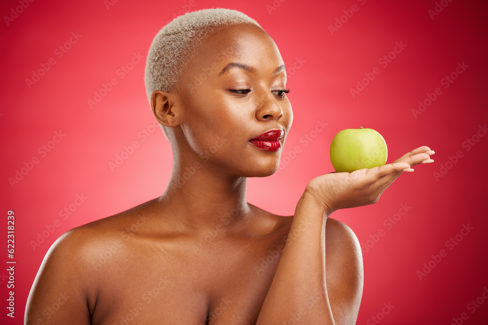 Black woman, apple and thinking for natural nutrition or healthy diet against a red studio backgroun