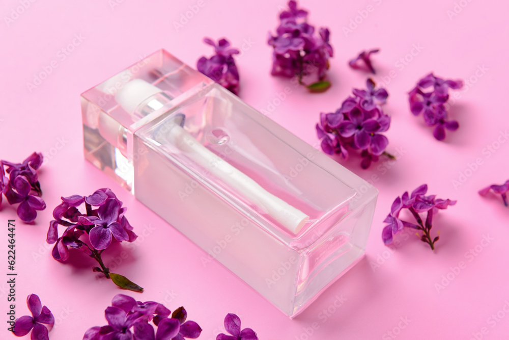 Beautiful lilac flowers and bottle of perfume on pink background, closeup