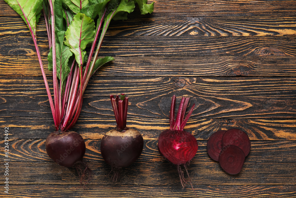Fresh beets with green leaves on wooden background