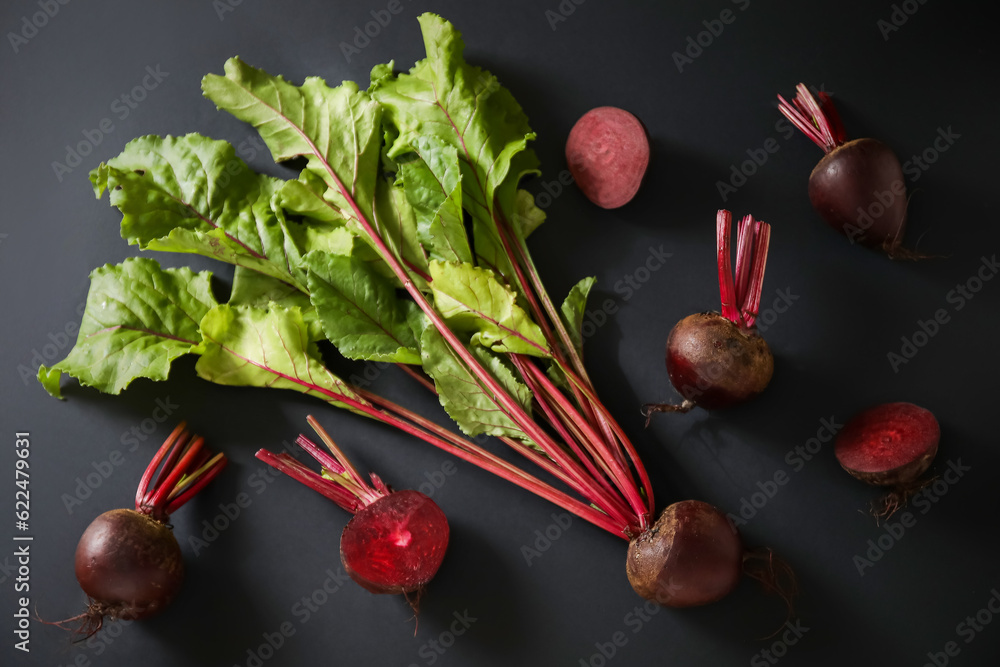 Fresh beets with green leaves on black background