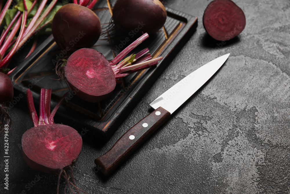 Wooden board of fresh beets on black background