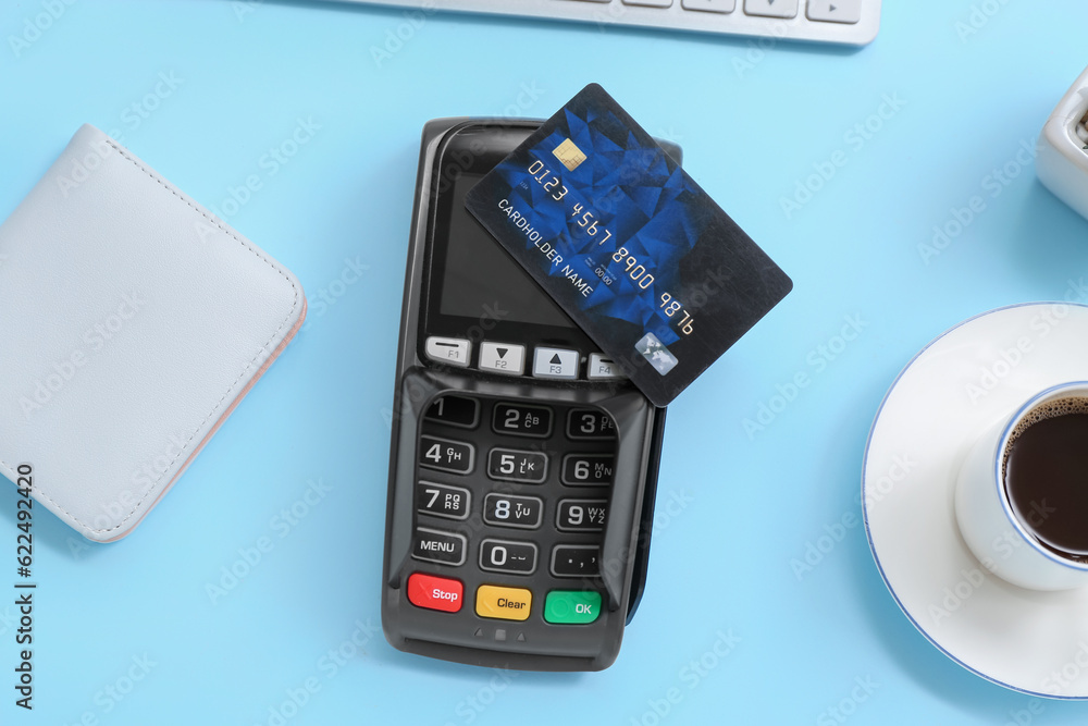 Payment terminal with wallet, cup of coffee and credit card on blue background