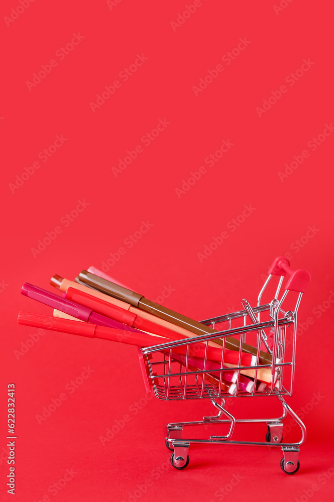 Shopping cart with felt-tip pens on red background