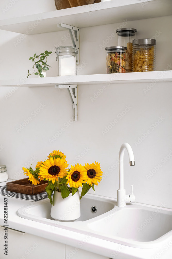 Vase with beautiful sunflowers in kitchen sink