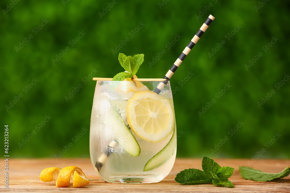 Glass of lemonade with cucumber and mint on wooden table outdoors