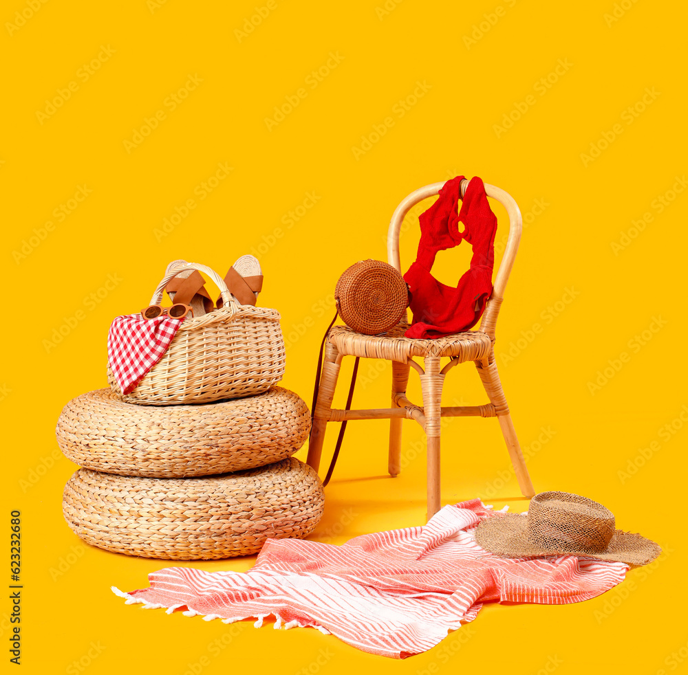 Chair with ottomans, wicker basket and beach accessories on yellow background. Travel concept