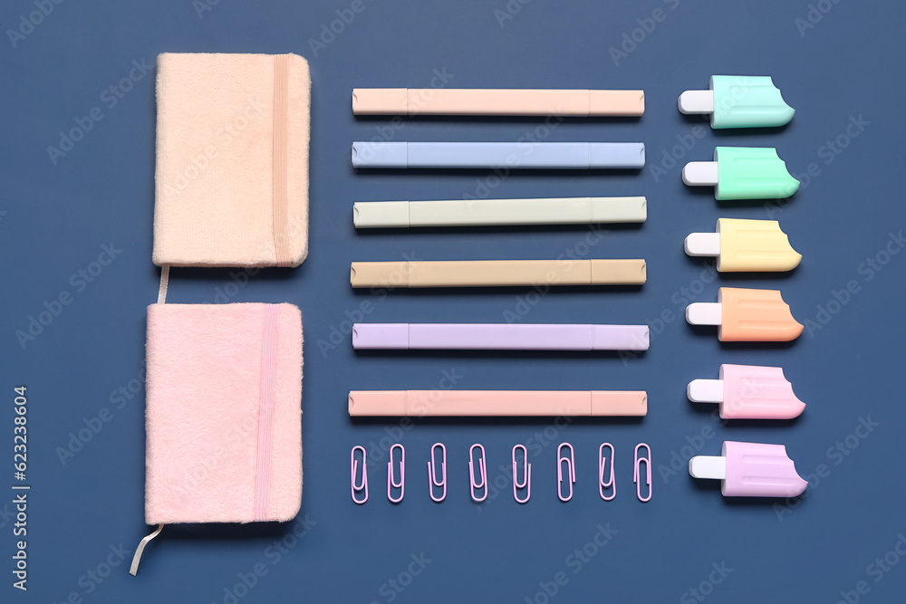 Stylish notebooks and markers in different shapes on blue background