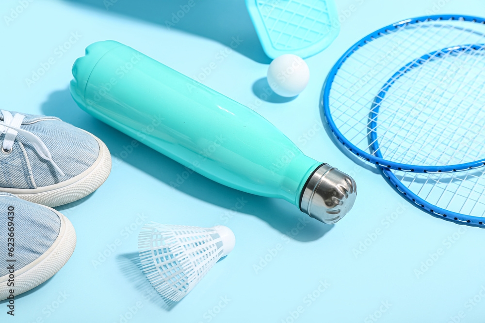 Bottle of water, shoes and sports equipment on color background