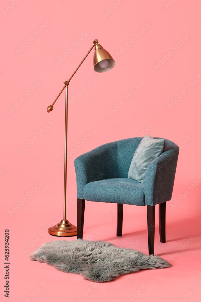 Soft armchair with lamp and fur carpet on pink background