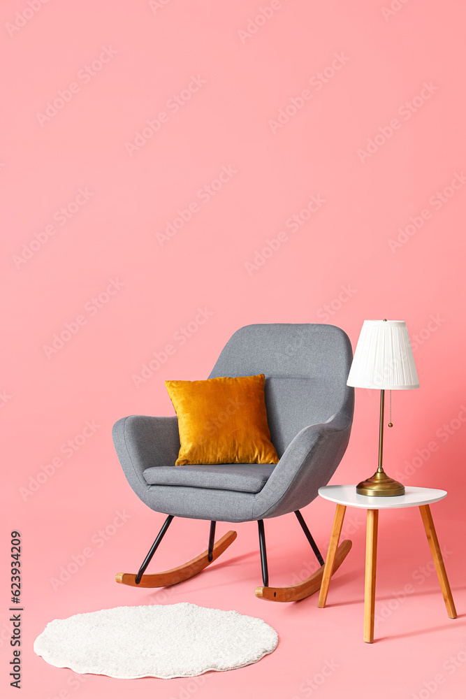 Rocking chair with table and rug on pink background