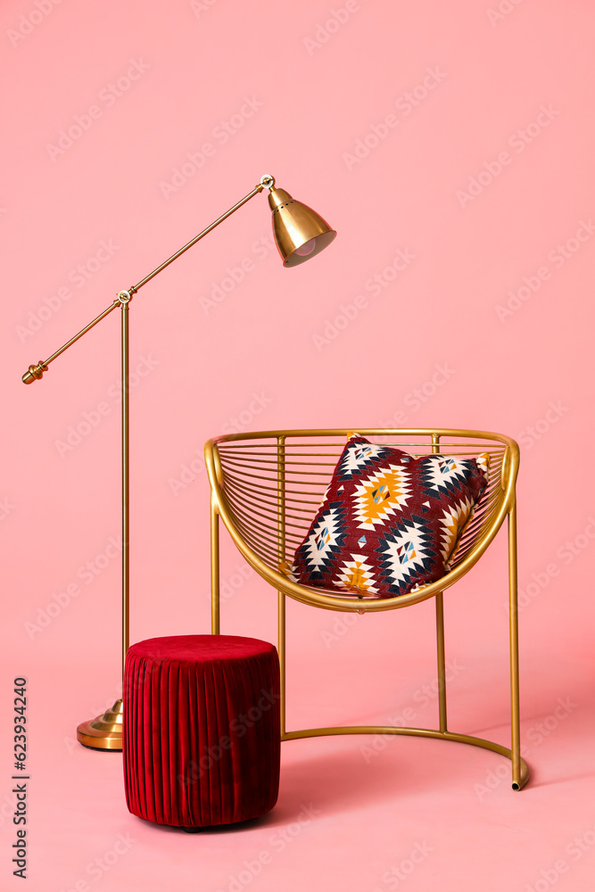 Golden armchair with pouf and lamp on pink background