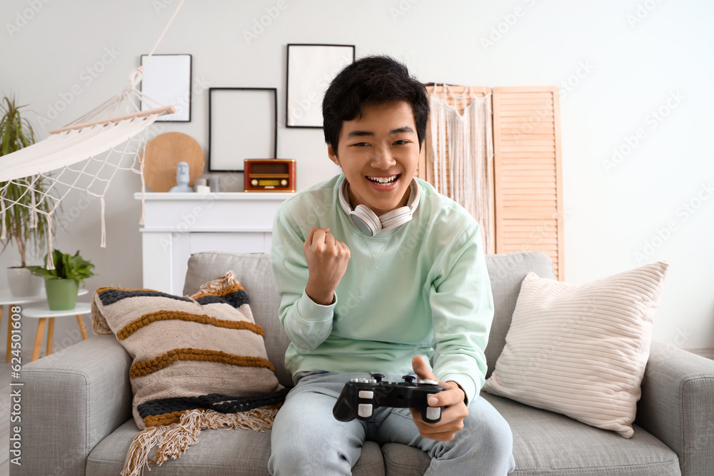Young Asian man playing video game on his day off at home