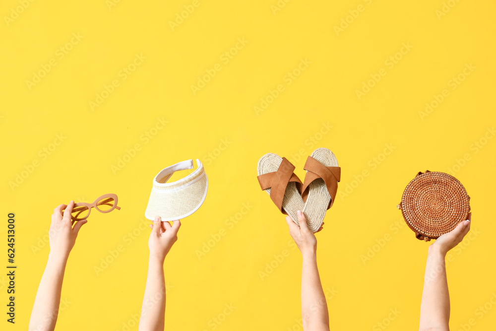 Many hands holding beach accessories on yellow background