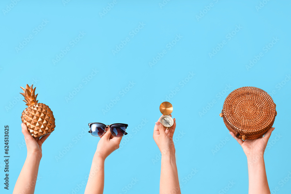 Female hands with beach accessories and compass on blue background